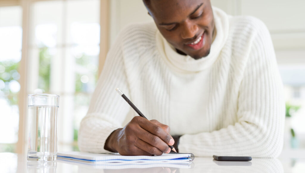 close up african man writing note paper smiling confident scaled e1719416724315